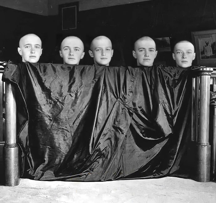 Five young men with shaved heads hidden under a large cloth in a rare and intriguing historical photo.