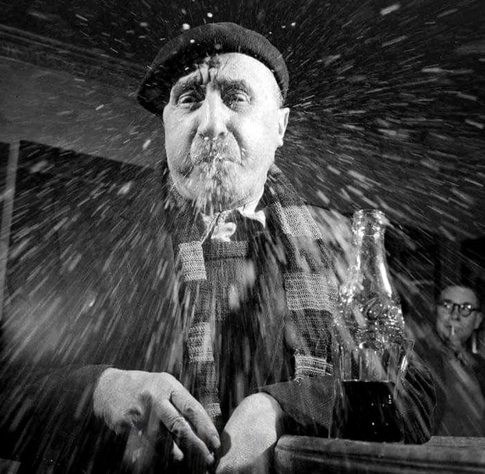 Elderly man in a beret and scarf spitting soda, captured in a rare and intriguing photo showing history between the headlines.