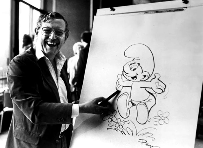 Black and white rare photo of a smiling man drawing a Smurf cartoon at an easel, showcasing history between the headlines.