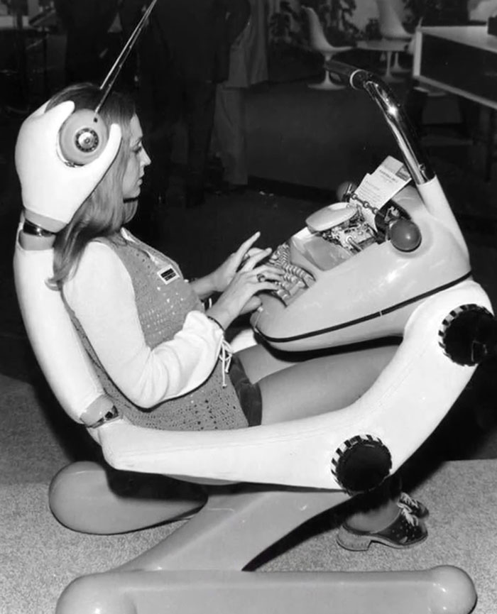 Woman typing on futuristic chair with built-in typewriter, showcasing rare and intriguing photos from history.
