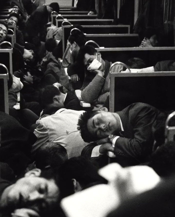 Black and white rare historical photo showing crowded train passengers sleeping in close quarters during a busy commute.