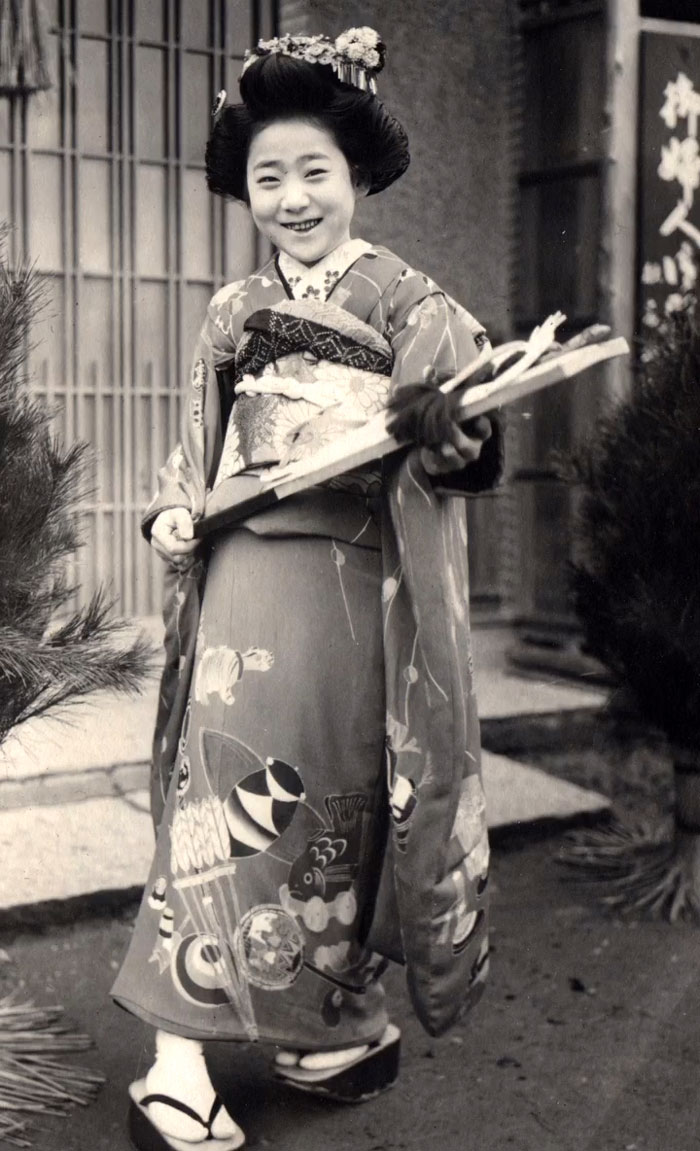 Young Japanese woman in traditional kimono holding decorative paddle, a rare and intriguing photo showing history between the headlines.