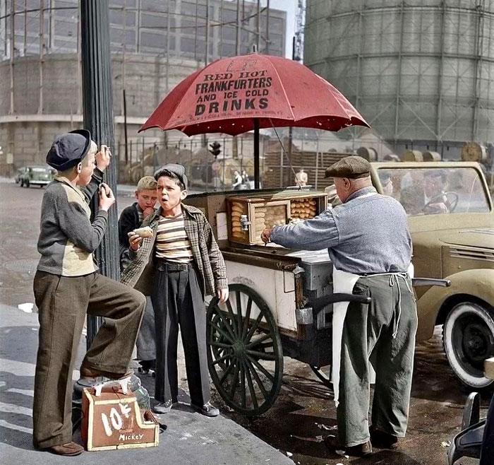 Boys buying frankfurters at a vintage street cart in a rare and intriguing historic photo showing life between headlines.