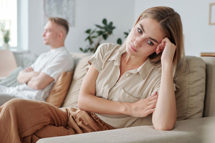 Frustrated woman and annoyed cheating guy having conflict on couch, hinting at ex-wife limo driver reality check.
