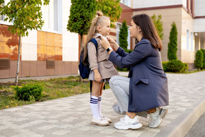Woman adjusting her daughter's clothing outdoors, illustrating a cheating guy's ex-wife and new kid situation.