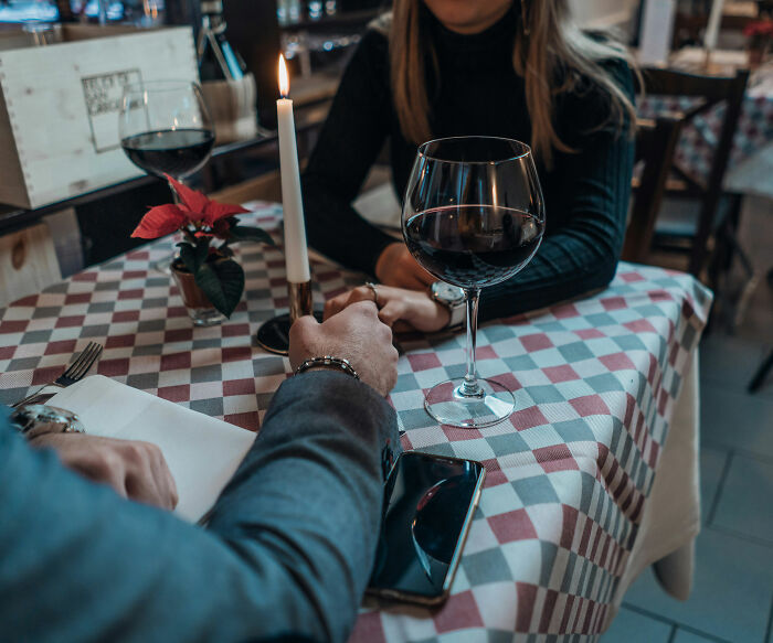 Couple holding hands at a restaurant table with wine glasses, illustrating a Florida man after a bad breakup story.