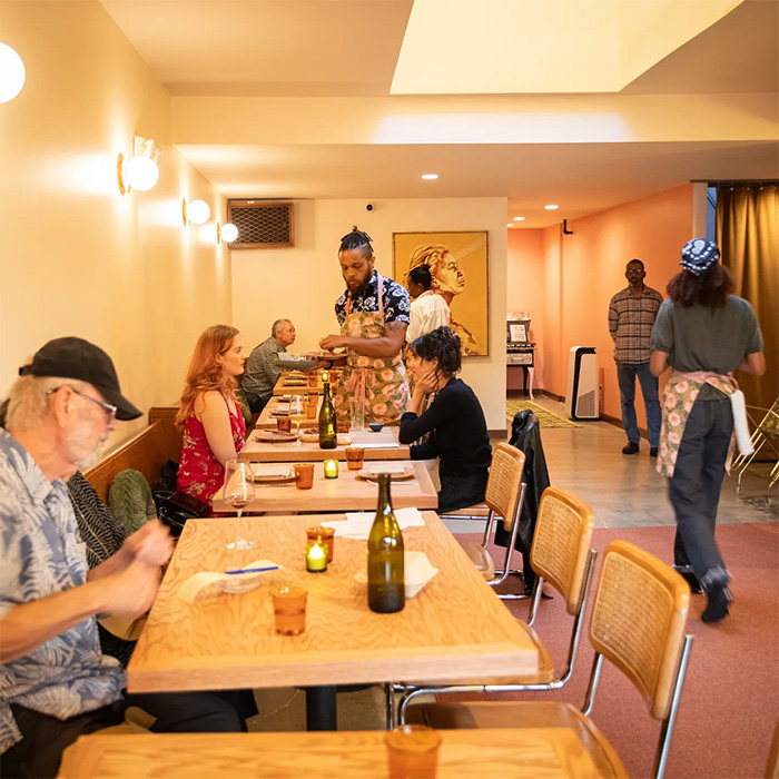 Diverse diners and servers in a top restaurant sparking outrage over automatic 20% tip policy and country's racist past.