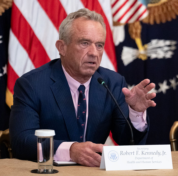 Robert F Kennedy Jr. speaking at a podium with U.S. flags behind him, related to his new workout video madness. Robert F Kennedy Jr. speaking at a podium with U.S. flags behind him, related to his new workout video madness.