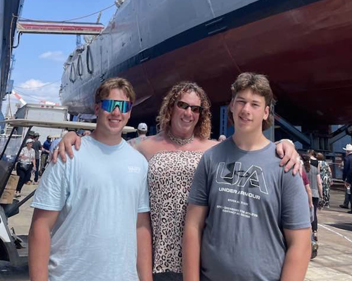 Family of trans mom Roberta Dorgan posing outdoors near a large ship during a public event.