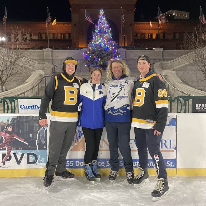 Family of trans mom Roberta Dorgan posing together on an ice rink with a decorated Christmas tree in the background.
