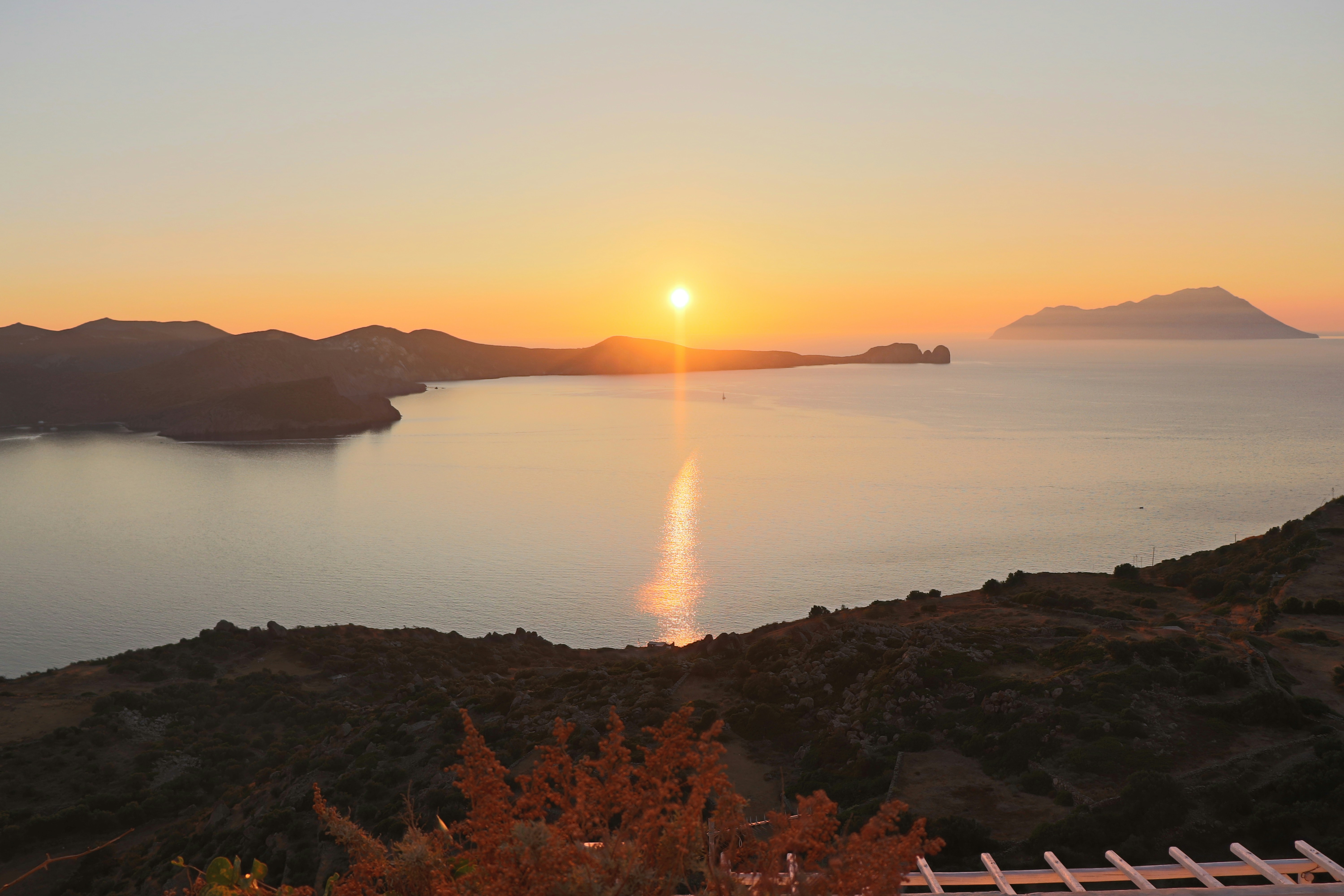 Sunset over calm sea and rugged coastline, symbolizing reflection on living out of a suitcase and questioning success. Sunset over calm sea and rugged coastline, symbolizing reflection on living out of a suitcase and questioning success.