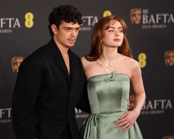 Sadie Sink at BAFTA event wearing green strapless dress alongside a man in black suit triggering divided reactions.