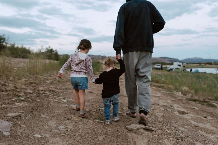 Adult walking with two children on rough outdoor path, illustrating dangerous things that are often dismissed by people.