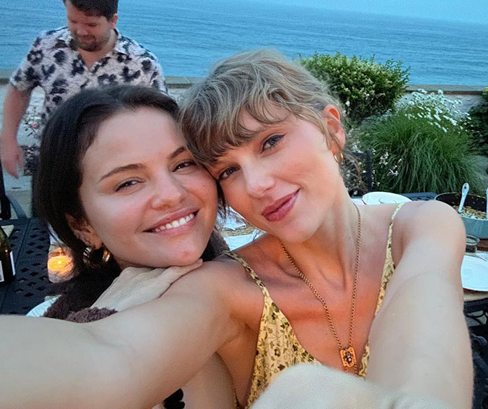 Taylor Swift and Selena Gomez smiling together outdoors near water, highlighting Taylor Swift's gift backlash.