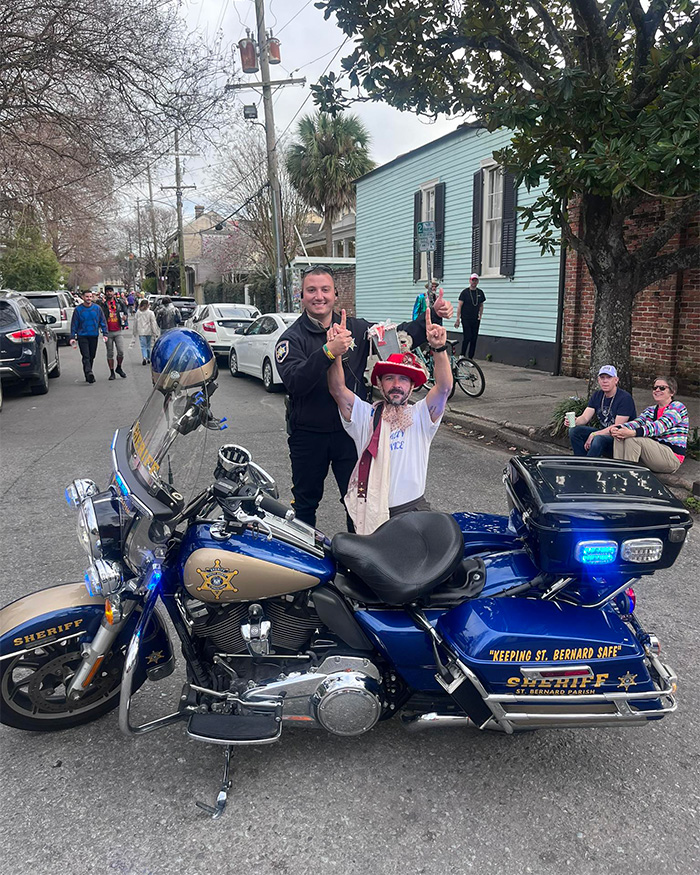 Police officer posing with a man next to a sheriff motorcycle during an arrest in New Orleans street scene.