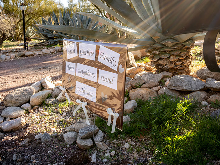 Support sign for Guthrie family outdoors near plants and rocks, related to Savannah Guthrie&rsquo;s brother-in-law and missing mom case.