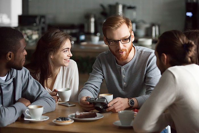 Group of friends at a café having a conversation, illustrating subtle signs of very low intelligence in social settings.