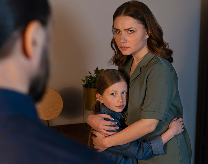 Woman and child looking worried and defensive while facing a man, illustrating subtle signs of low intelligence.