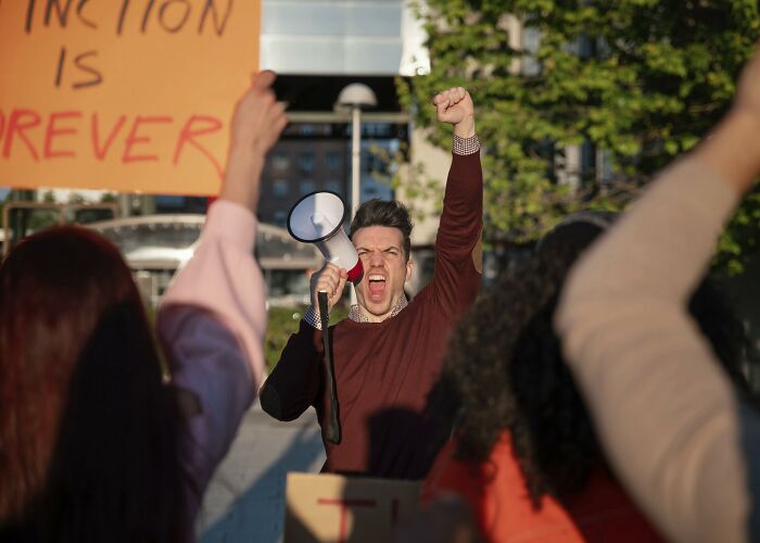 Man shouting into a megaphone at a protest, illustrating signs of very low intelligence in a public setting.