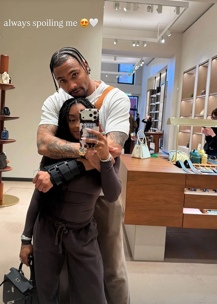 Simone Biles and NFL husband embracing in store mirror selfie during their Winter Olympics visit.