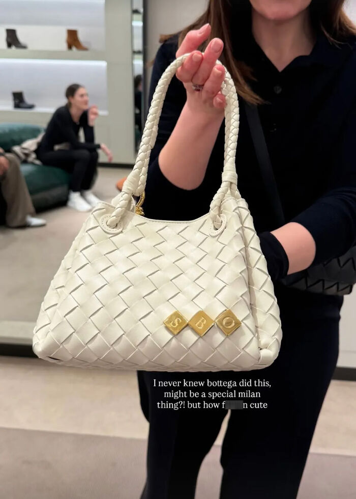 Woman holding a white woven bag with gold letter charms, related to Simone Biles and NFL husband unsettled crime story.