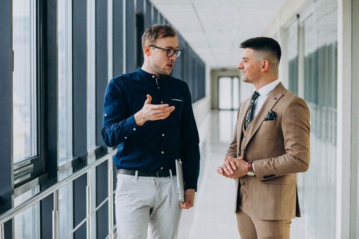 Two men having a serious conversation in a hallway, illustrating sister relationship cheater work drama concept.
