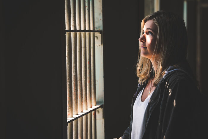 Woman looking through prison bars with a thoughtful expression, illustrating lawyers confessing surprising information.