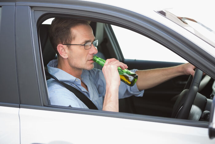 Man drinking alcohol while driving a car, illustrating one piece of information that shocked many lawyers.
