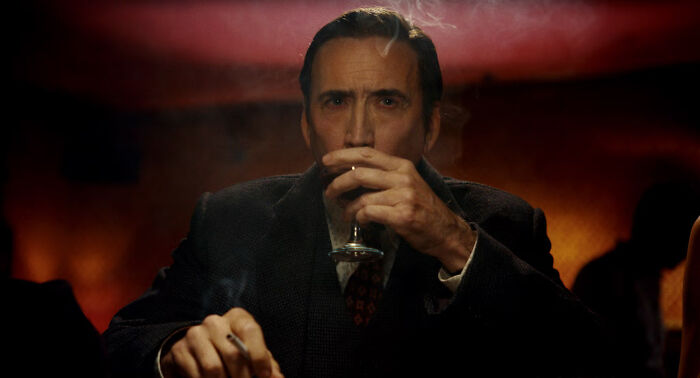 Man in dark suit holding a glass and cigarette, with moody lighting highlighting Spider-Noir powers and origin theme.