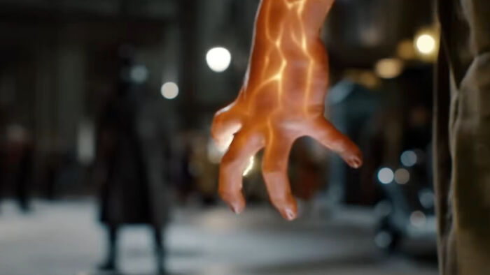 Glowing orange hand of a Spider-Noir villain reaching out with blurred figure in the dark urban background. Glowing orange hand of a Spider-Noir villain reaching out with blurred figure in the dark urban background.