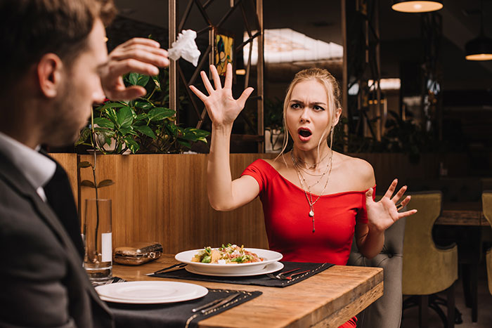 Woman in red dress reacting shocked at restaurant after guy's planned proposal ring ends up in another woman's dessert