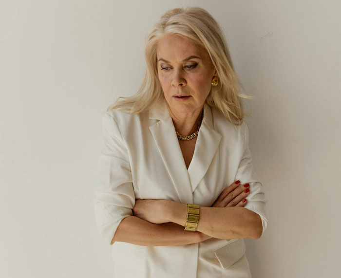 Woman in white blazer with arms crossed, looking concerned, relating to step-mom food stealing and CPS visit issues.