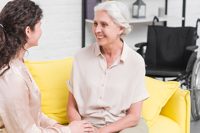 Older woman and younger woman having a heartfelt conversation on a yellow couch, reflecting on lying and broken relationship issues.
