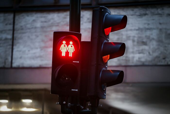 Red pedestrian traffic light showing two human figures holding hands, evoking strange things people witnessed that made them question.