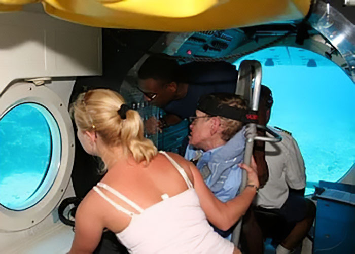 Stephen Hawking e grupo dentro de um submarino, explorando o fundo do mar através de uma janela redonda em um espaço confinado. Stephen Hawking e grupo dentro de um submarino, explorando o fundo do mar através de uma janela redonda em um espaço confinado.
