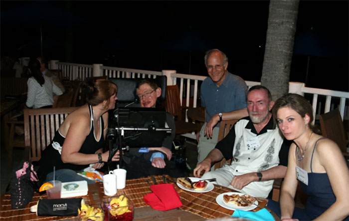 Stephen Hawking com familiares e amigos sentados em uma mesa ao ar livre, relatou arquivos de Epstein e reações cômicas. Stephen Hawking com familiares e amigos sentados em uma mesa ao ar livre, relatou arquivos de Epstein e reações cômicas.