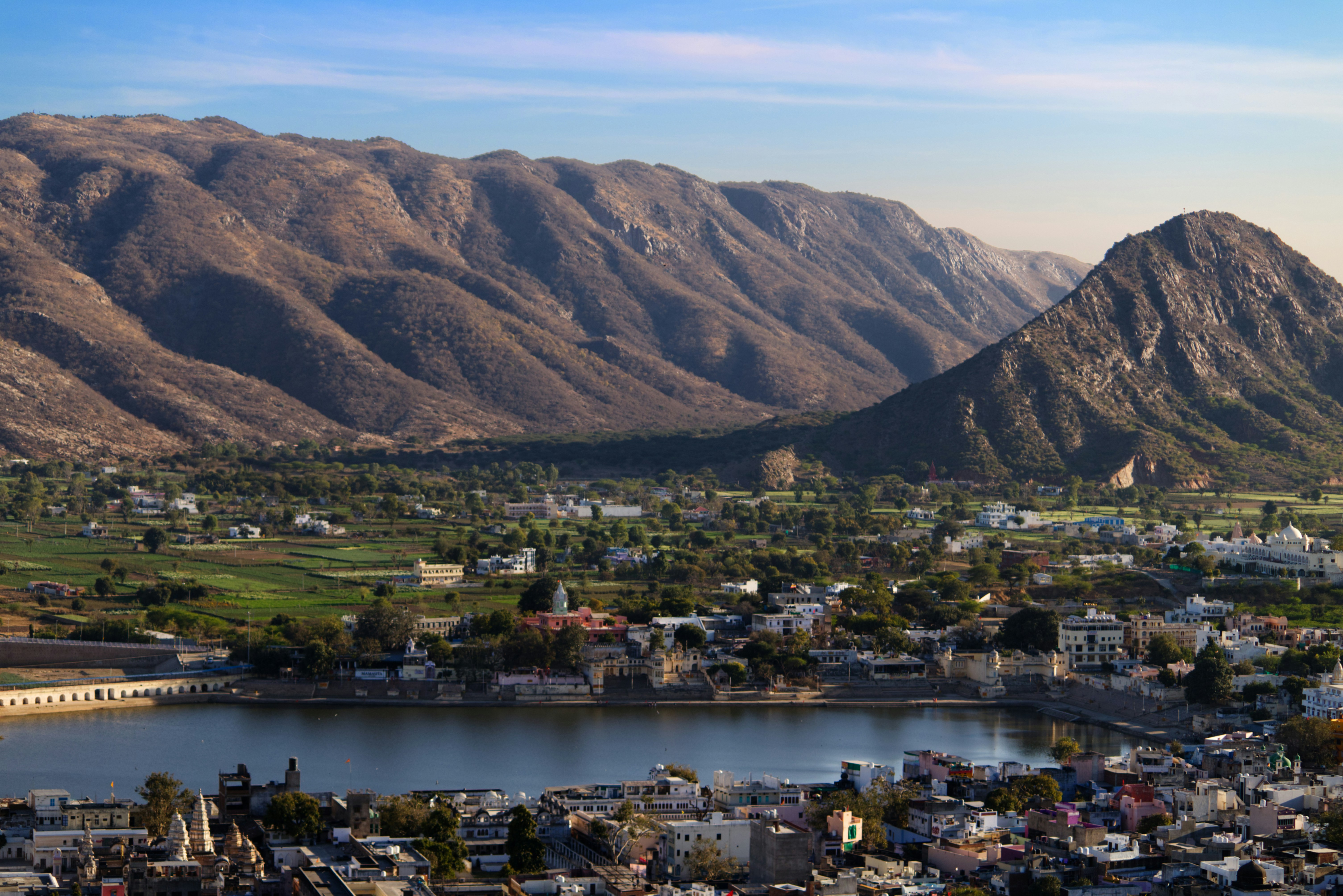 Scenic view of an Indian town by the water with mountains in the background, illustrating spiritual tourism in India.