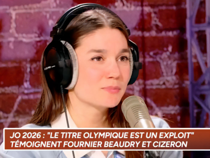 Young woman wearing headphones speaking into a microphone amid French ice skaters Olympic cheating scandal fury.