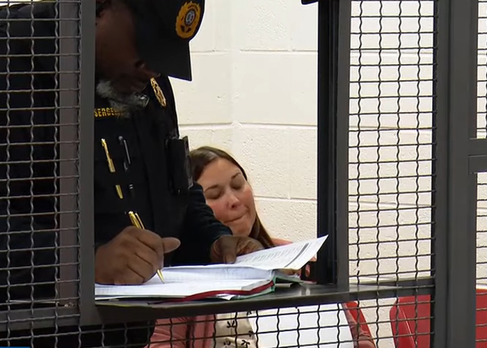 Police officer processing teacher jailed over alleged racist attack inside a detention area with woman sitting in the background. Police officer processing teacher jailed over alleged racist attack inside a detention area with woman sitting in the background.