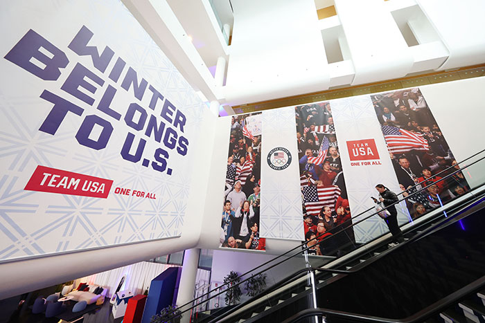 Large Team USA Olympics banners displayed indoors with a person on escalator, related to Tate McRae nationality controversy.
