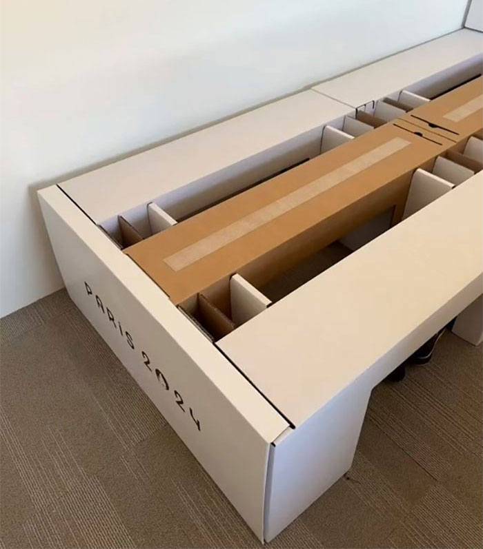 Cardboard bed frame labeled Paris 2024 inside a room, related to Winter Olympics athlete rooms and arrangements.