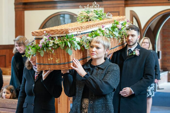 Mourners carrying a flower-adorned coffin inside a church, reflecting on toxic workplace moments affecting employees.