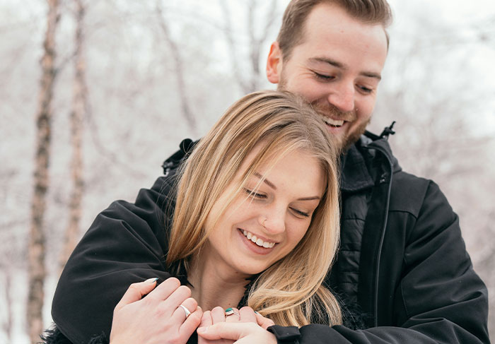 Young couple embracing outdoors in winter, illustrating behaviors related to dealing with a man-child in relationships