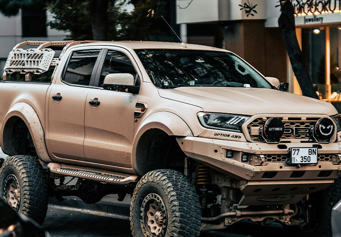 Beige lifted off-road truck parked on a city street, illustrating man-child behaviors with rugged and immature style.
