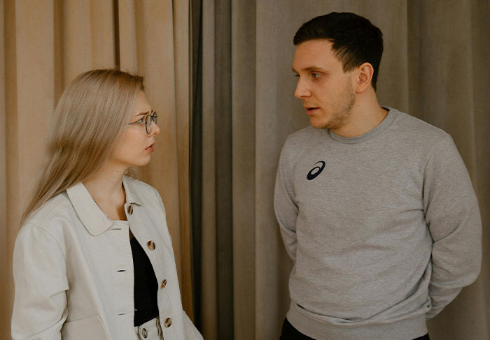 Young man and woman having a serious conversation indoors, illustrating common man-child behaviors in relationships.