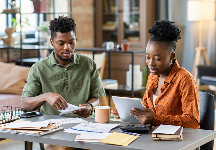 Man and woman reviewing documents and using tablet at home, illustrating behaviors of a man-child in relationships.