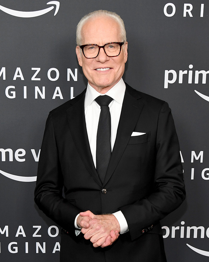 Tim Gunn in a black suit and glasses at an Amazon Originals event, discussing celibacy in a formal setting.