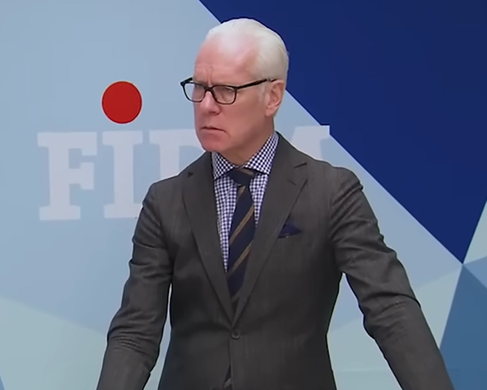 Tim Gunn dressed in a suit and glasses speaking at an event about celibacy and personal reflections.