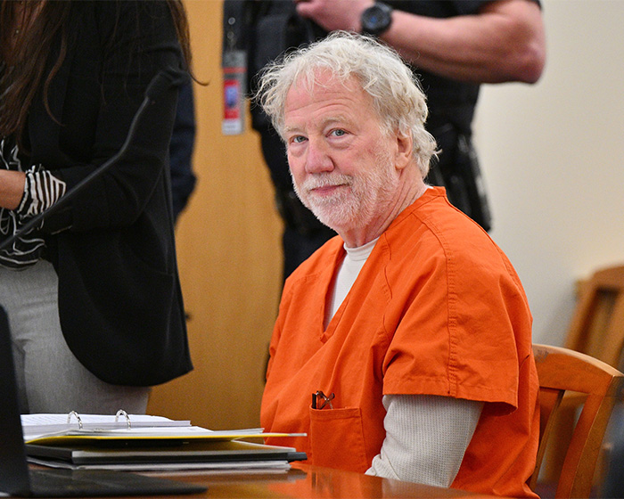 Man in an orange prison jumpsuit sits at a courtroom table during a serious child case involving Timothy Busfield.