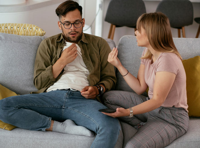 Tired woman and man having a serious conversation on couch, illustrating quiet quit in marriage and emotional distance.